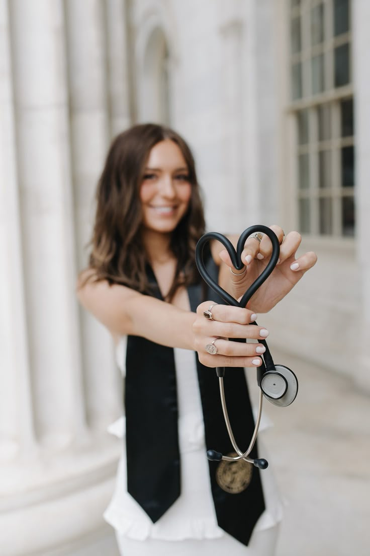 a woman holding up a stethoscope in front of a building