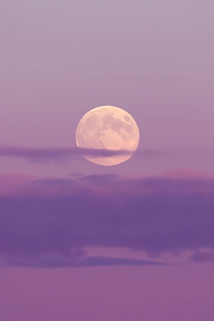 the full moon is shining brightly in the purple sky above some trees and clouds,