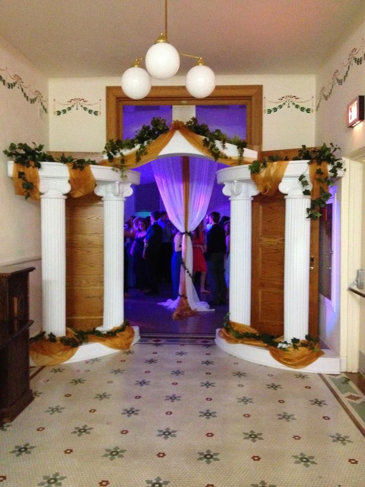 an archway decorated with flowers and greenery for a wedding ceremony at the end of a hall