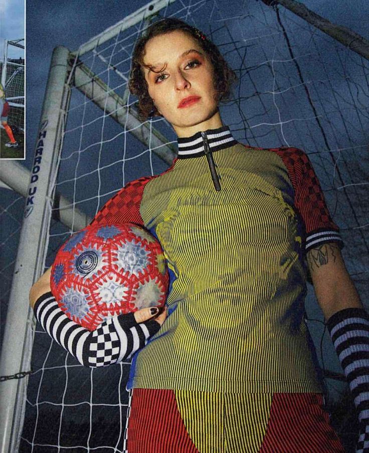 a woman holding a soccer ball in front of a net