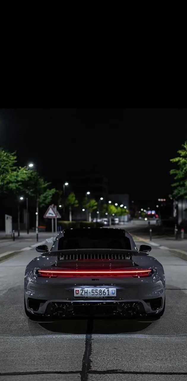 a black sports car parked on the side of the road at night with its lights on