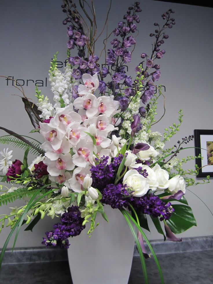 a white vase filled with lots of purple and white flowers