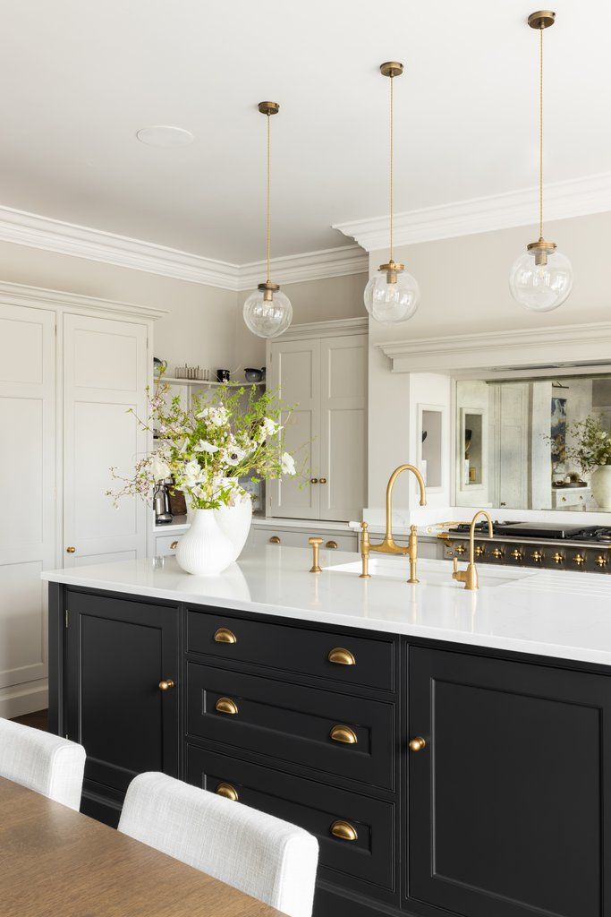 a kitchen with black cabinets, white countertops and gold pulls on the handles is shown