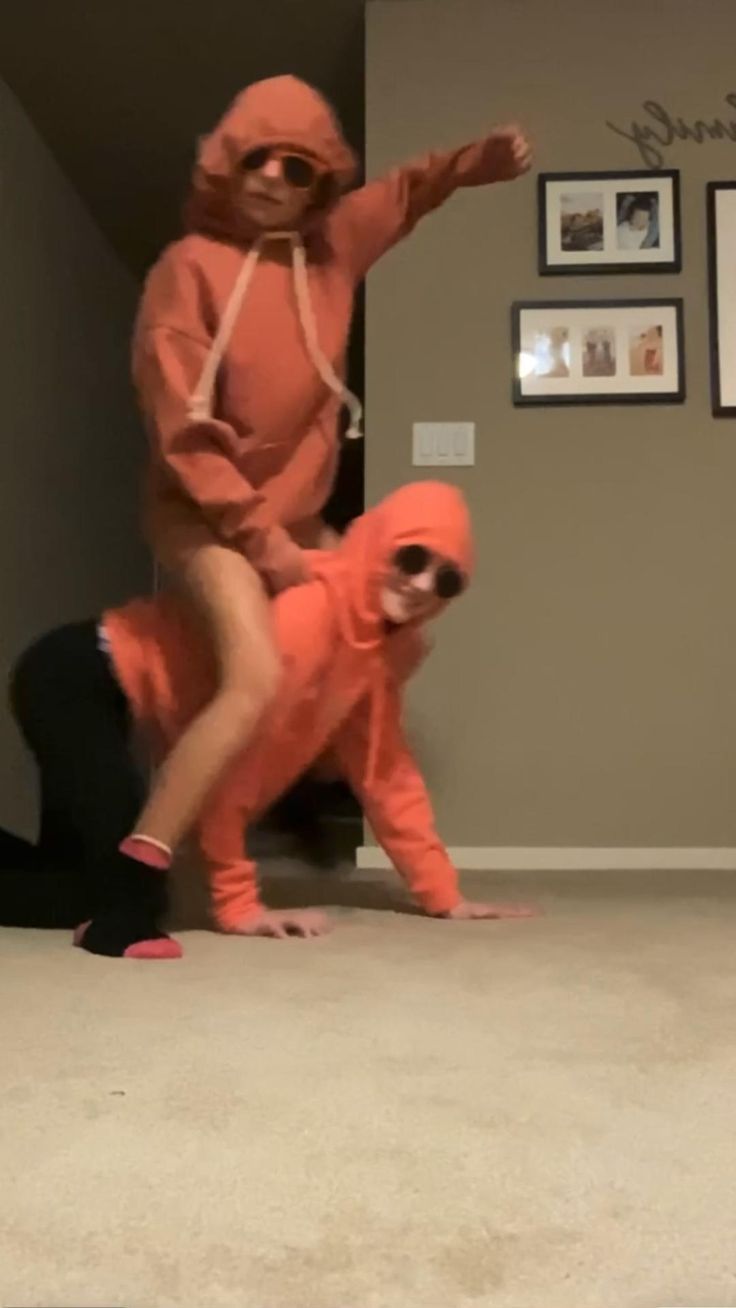 two people dressed in orange are dancing on the floor with one person wearing an orange costume