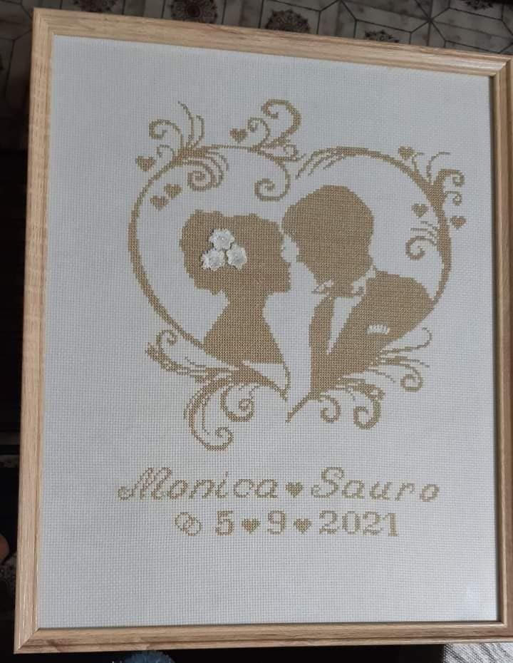 a cross stitch picture frame with a couple kissing in the shape of a heart on it