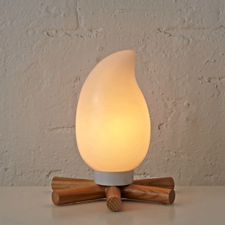 a white light sitting on top of a wooden stick next to a wall and some wood sticks