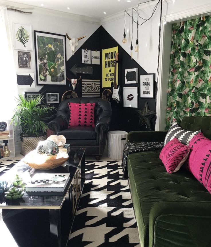 a black and white living room with green couches, pink pillows and pictures on the wall