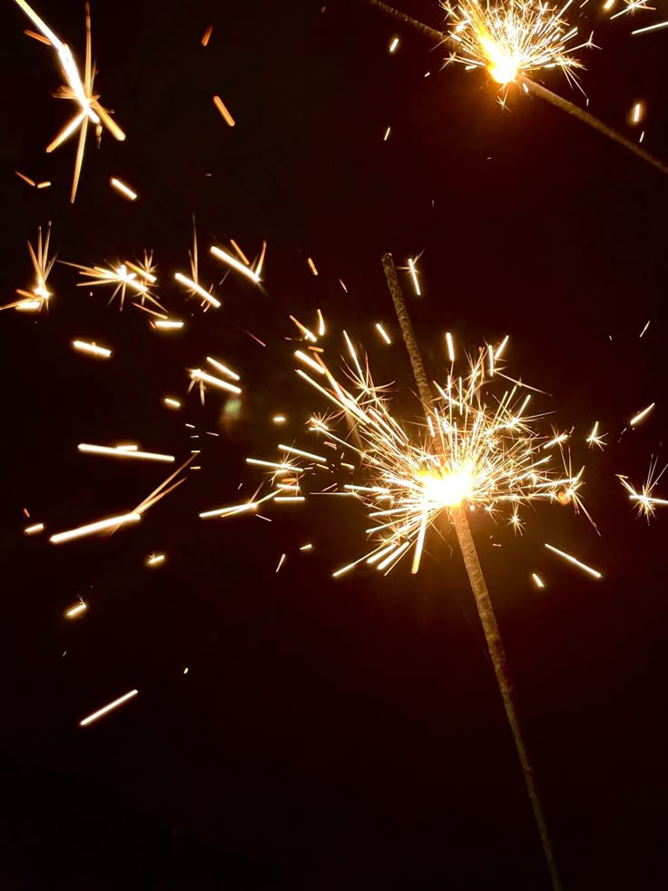 two sparklers that are lit up in the dark