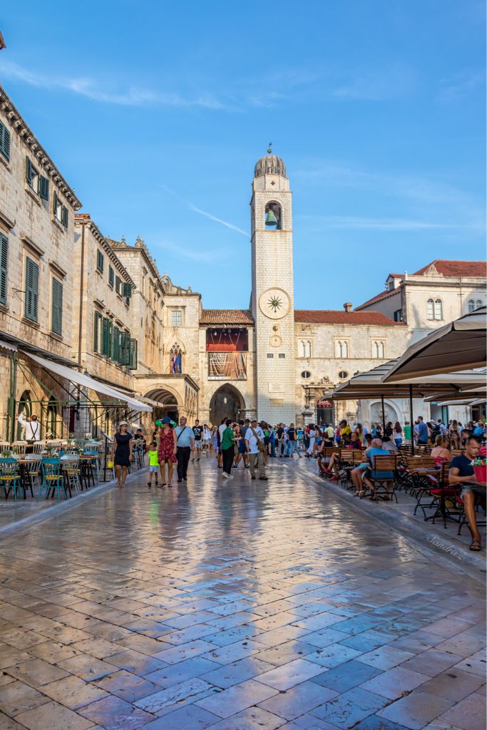 people are walking around in an old town square with tables and chairs on the ground