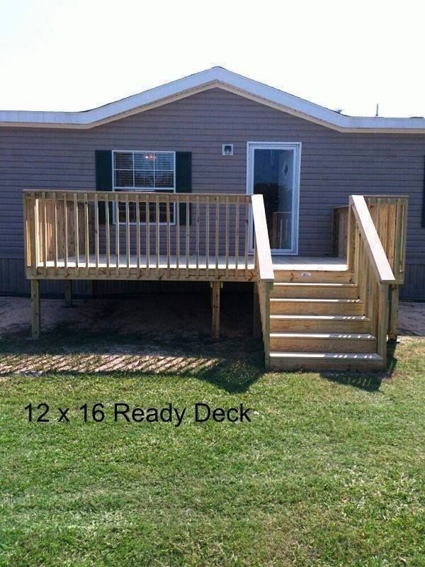 a deck with steps leading up to the front door and back porch area, next to a mobile home