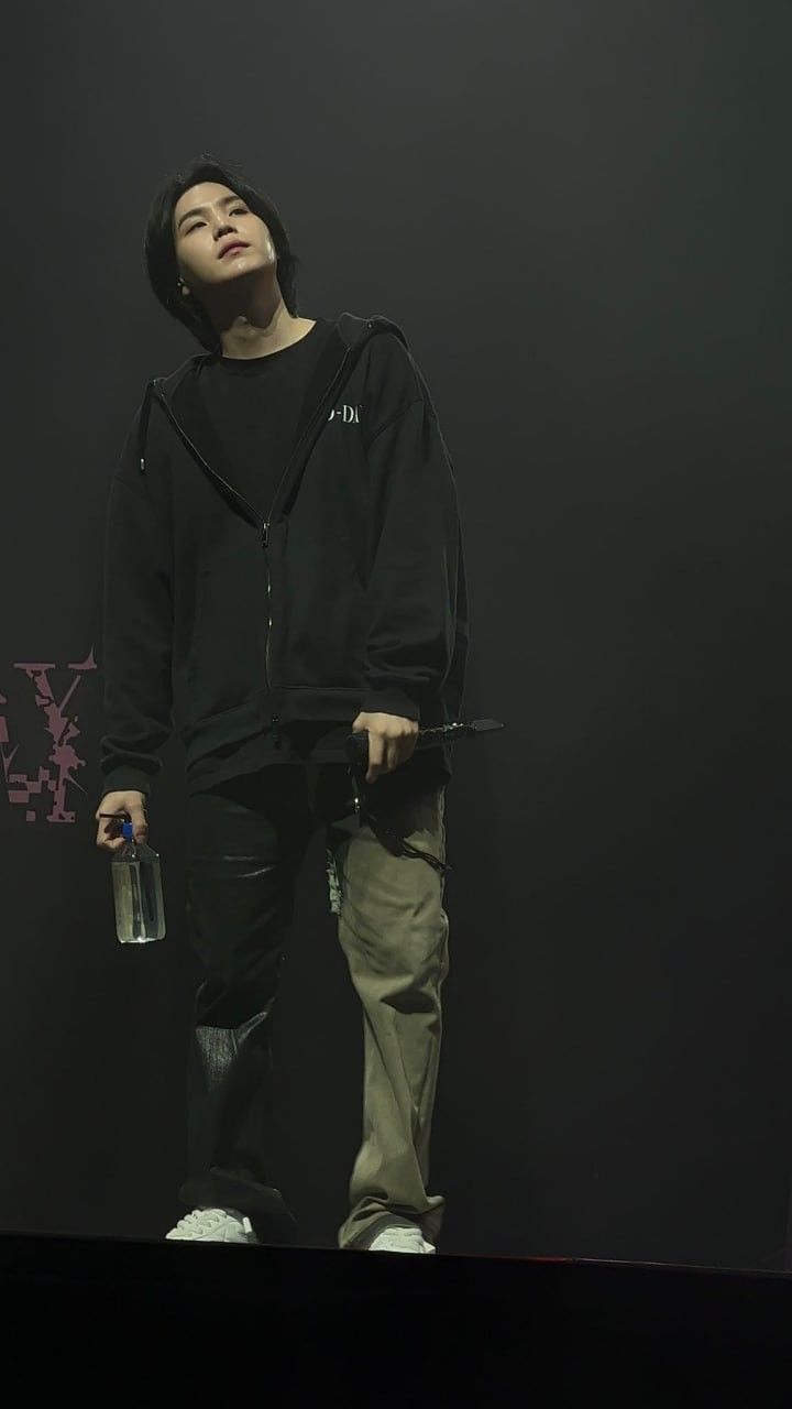 a man in black hoodie and khaki pants holding a water bottle