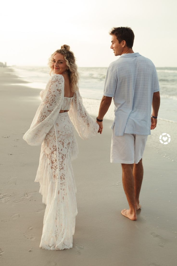 a man and woman walking on the beach holding hands