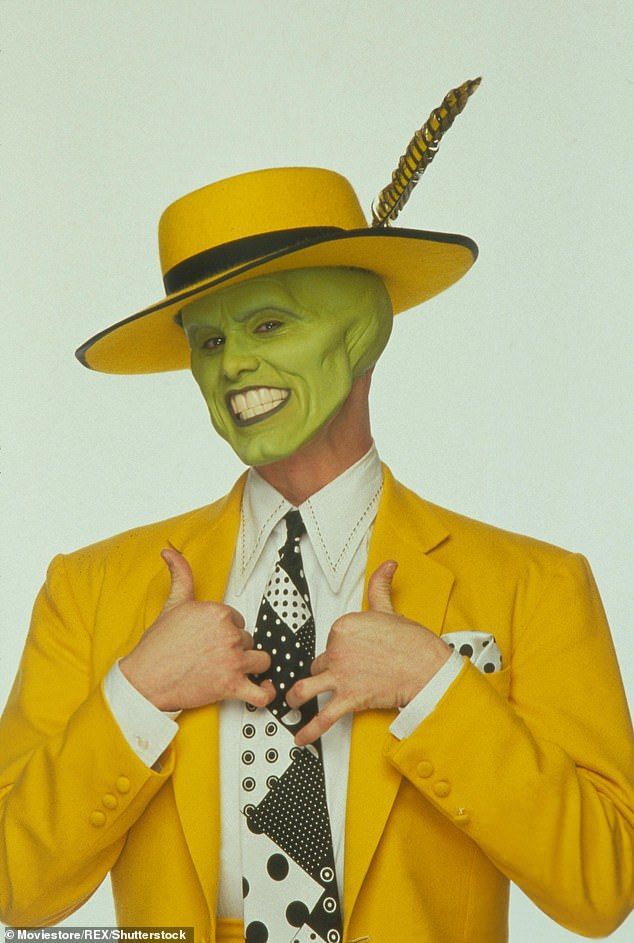 a man in a yellow suit and hat with his hands on his chest wearing a green mask