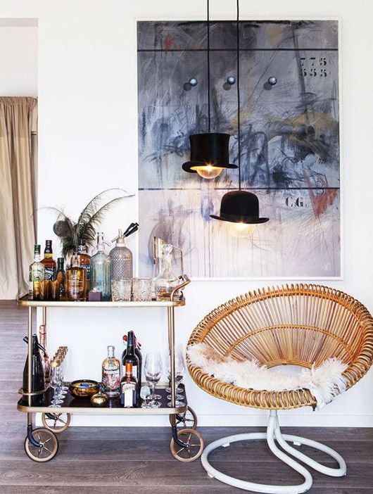 a wicker chair sitting on top of a wooden floor next to a shelf filled with bottles