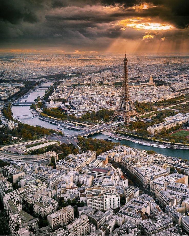 the eiffel tower towering over paris, france at sunset with sunbeams