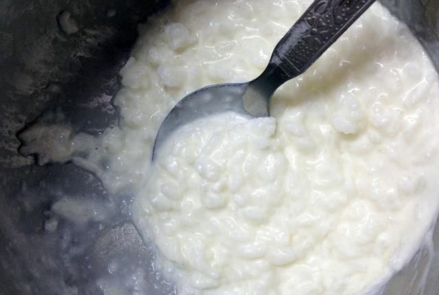 a spoon in a pot filled with white rice and water next to a spatula