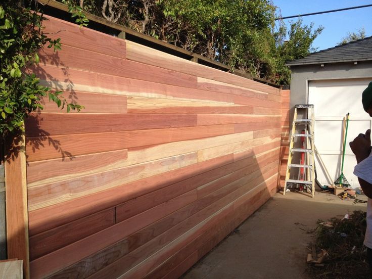 a man standing next to a wooden fence