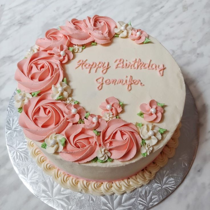 a birthday cake decorated with pink roses and white frosting