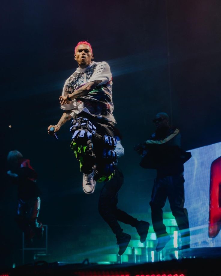 a man is performing on stage with his arms in the air