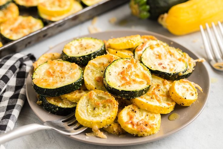 zucchini on a plate with a fork next to it and other food items