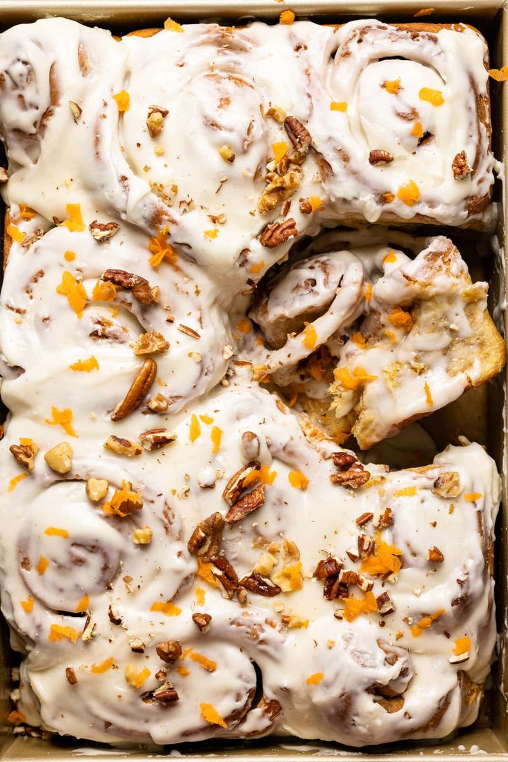 a box filled with glazed donuts covered in icing and orange zests