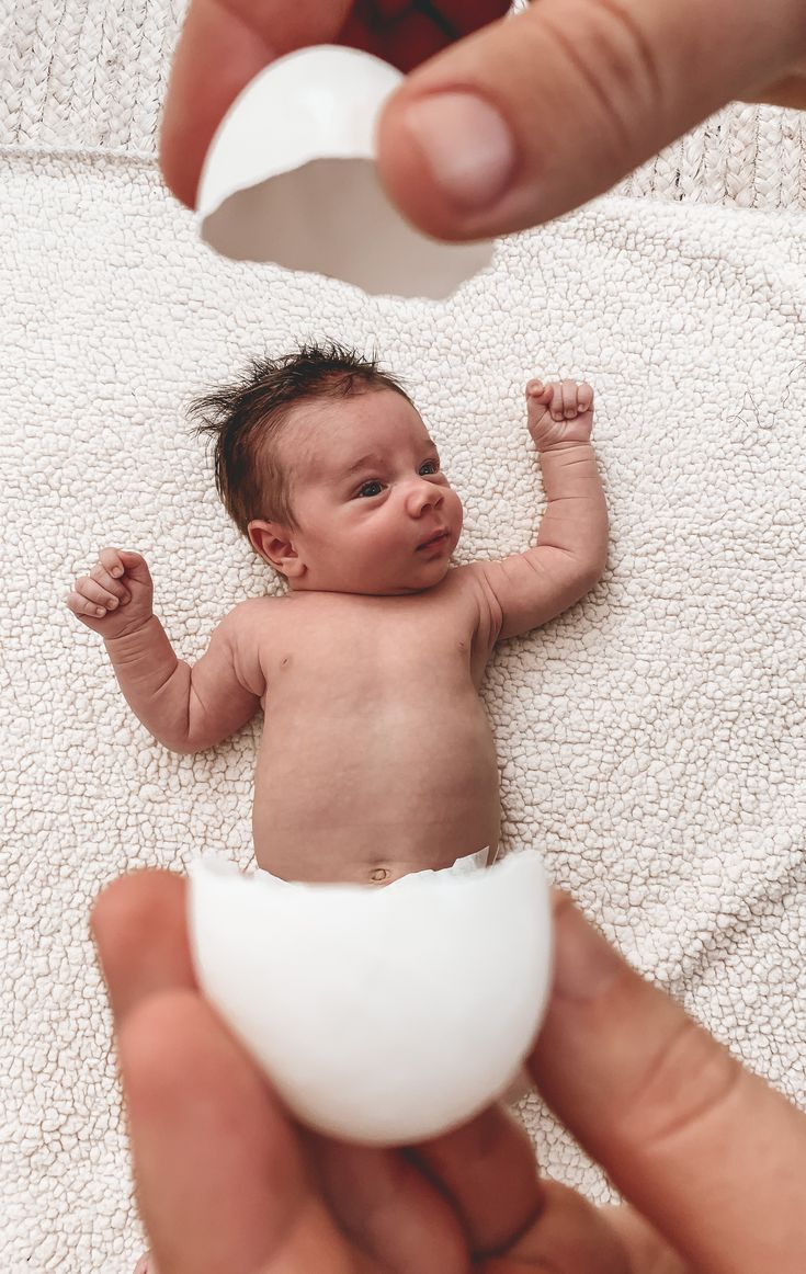 a baby is being held by someone holding an egg in it's hand,