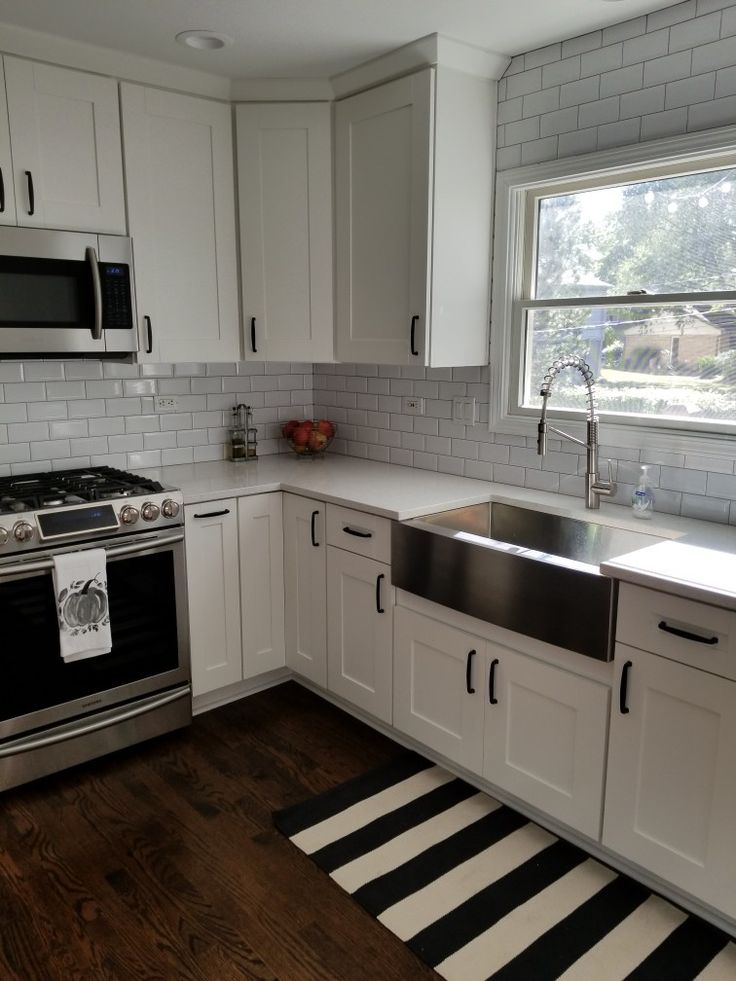 a kitchen with white cabinets and black and white striped rug on the floor next to the stove