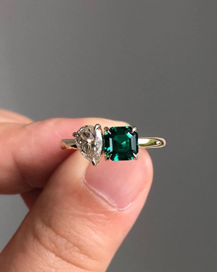 a person holding an emerald and diamond ring