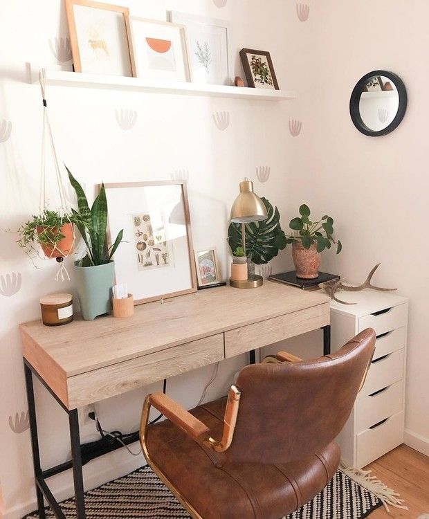 a desk with a chair, potted plants and pictures on the wall above it