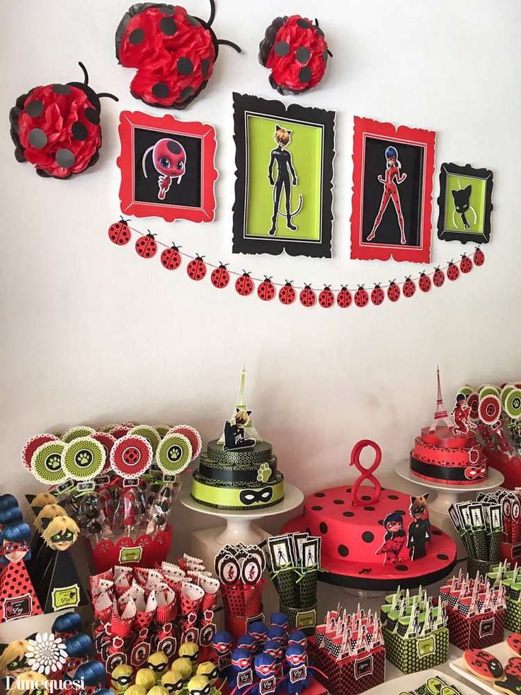 a table filled with lots of red and green items on top of white walls next to framed pictures