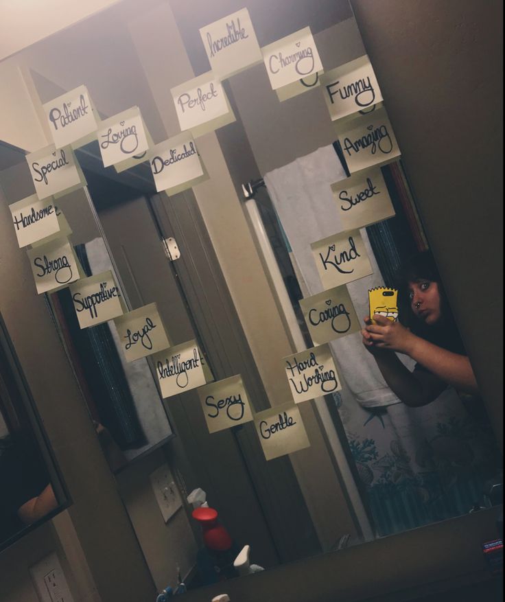 a person taking a selfie in front of a mirror with sticky notes on it