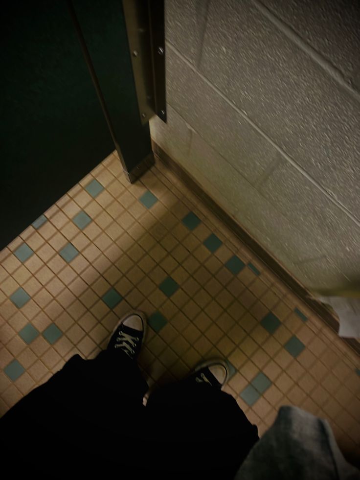 a person standing in front of a door on a tiled floor with blue and white tiles