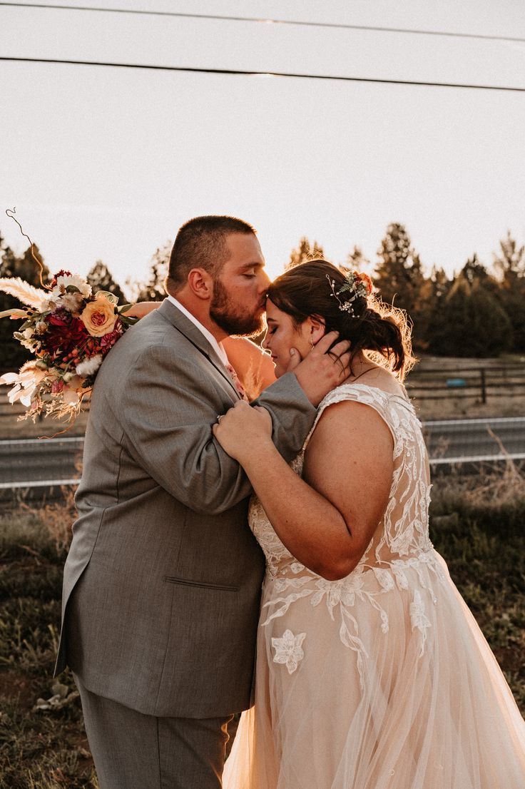 a bride and groom embracing each other in front of an empty road with power lines behind them