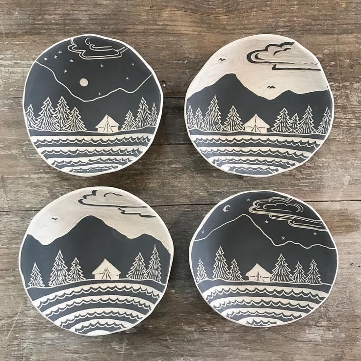 four black and white plates sitting on top of a wooden table