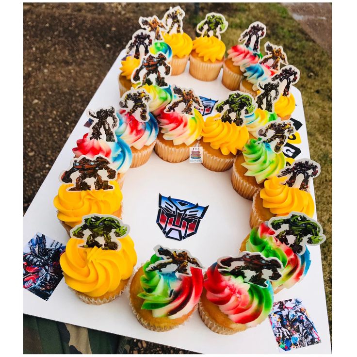 a table topped with lots of cupcakes covered in frosting and colorful icing