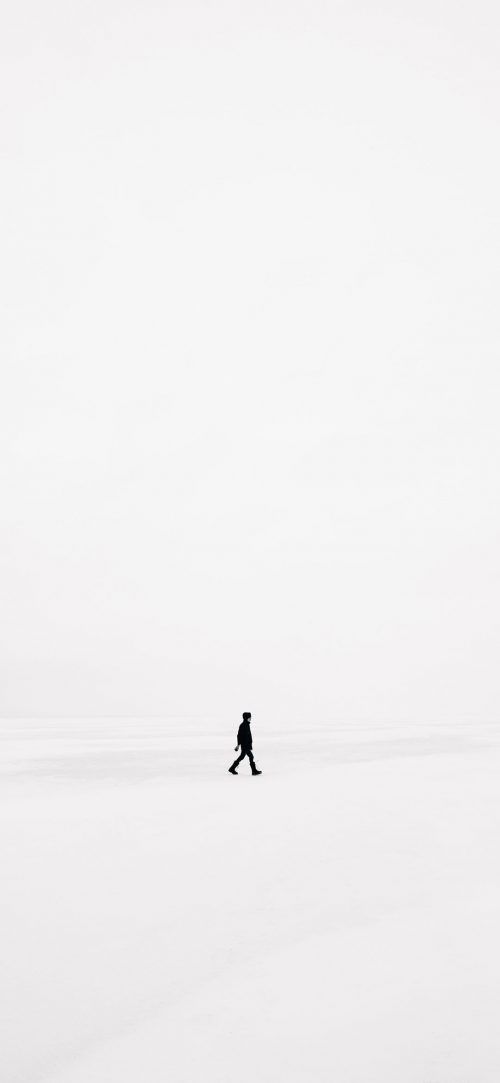 a lone person walking through the snow on a cold day with no one in sight