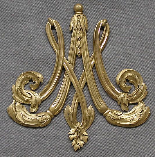 an ornate gold metal object on a gray background