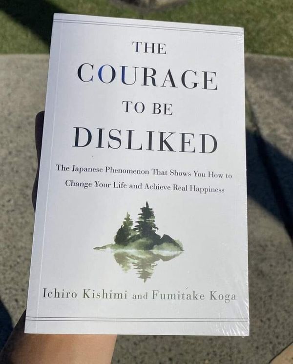 a person holding up a book in front of their face with the title, the courage to be disliked