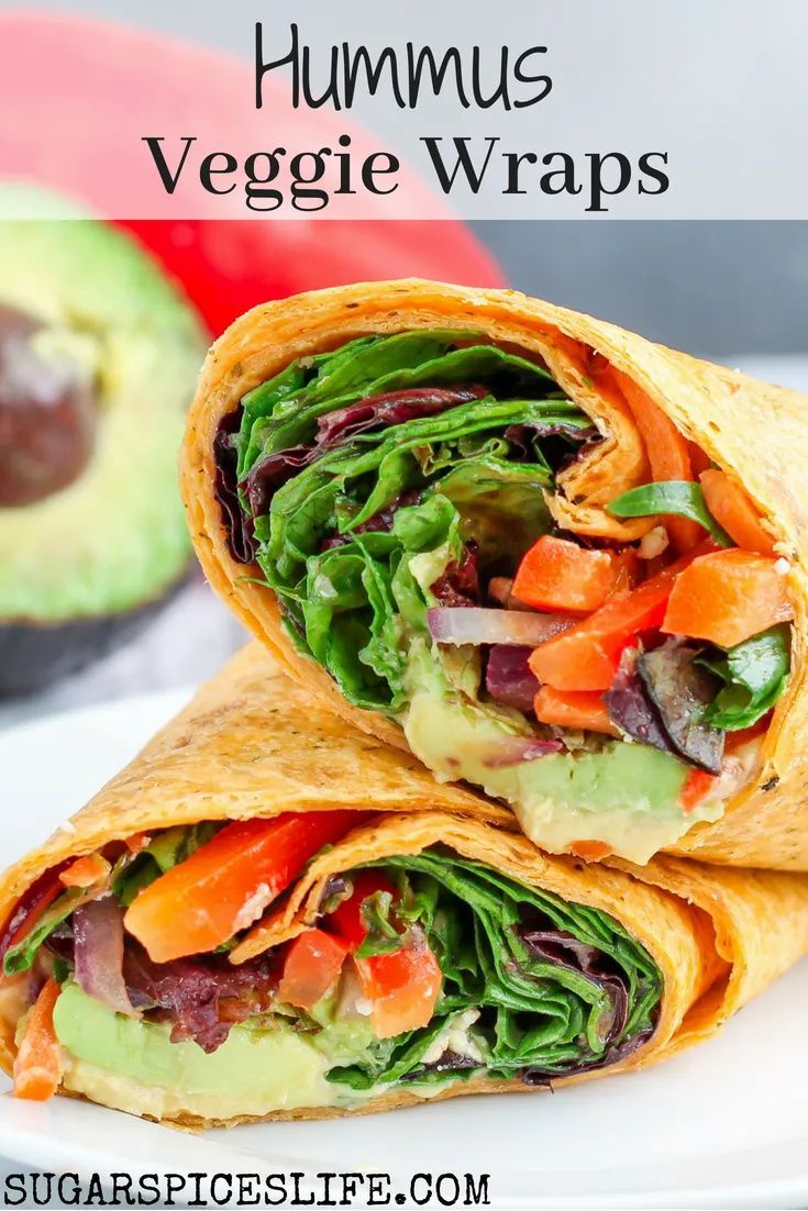 two wraps filled with veggies sitting on top of a white plate next to an avocado