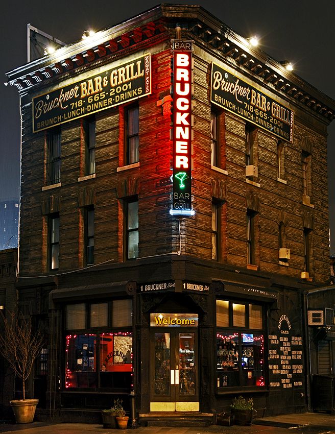 an old brick building with neon lights on the front and side of it at night