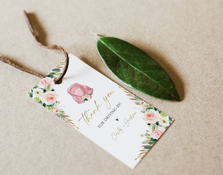 a thank you card with flowers and leaves on the ground next to it is a green leaf