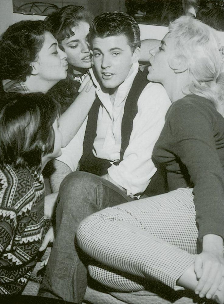 black and white photograph of four people sitting on a couch with one woman kissing the other