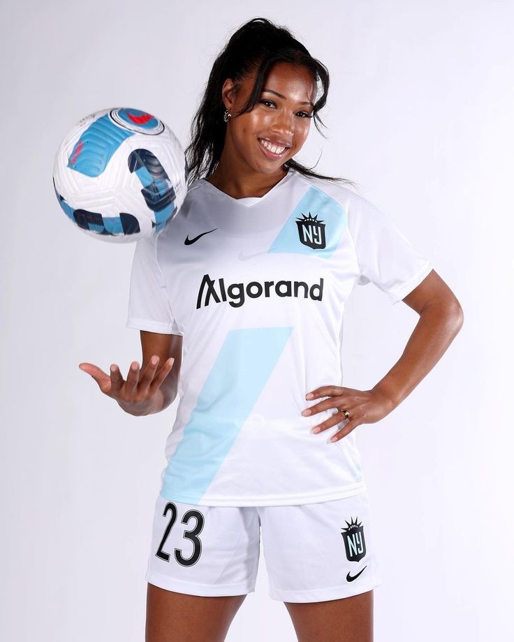 a woman holding a soccer ball in her right hand