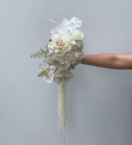 a bridal bouquet with white flowers is being held by a woman's hand