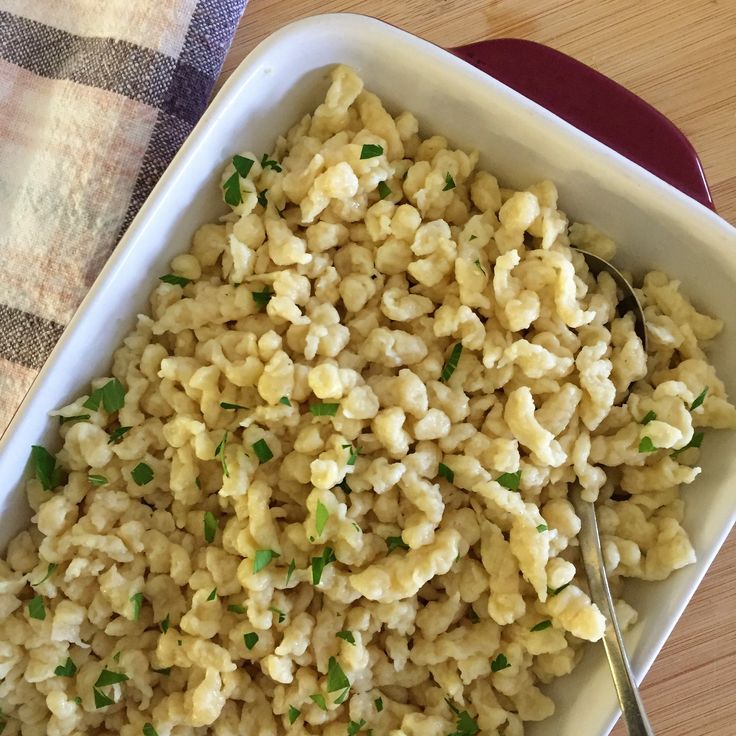 a white dish filled with macaroni and cheese on top of a wooden table