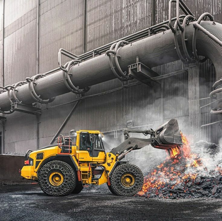 a yellow bulldozer excavating coal in front of a large industrial building