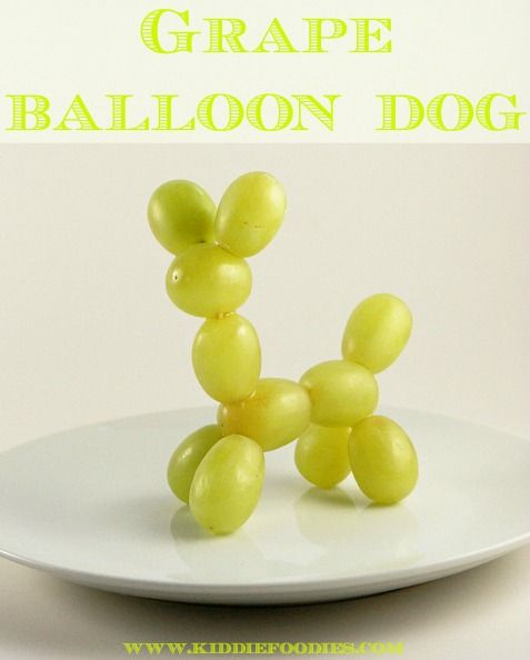 a white plate topped with grapes shaped like a balloon dog sitting on top of it