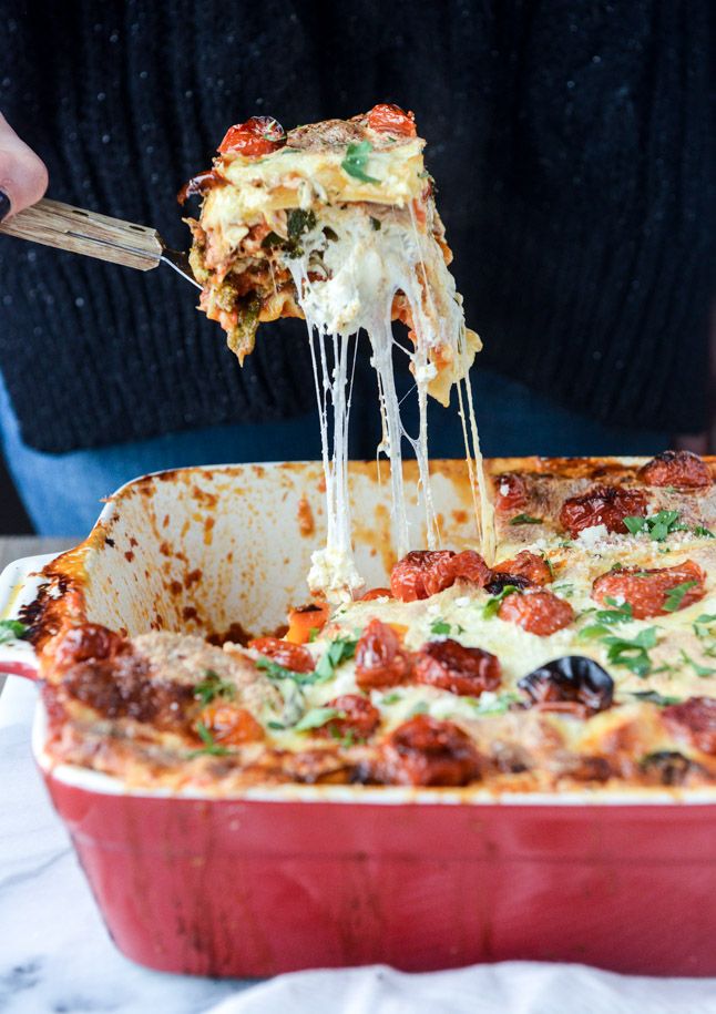 a person taking a slice of pizza from a red casserole dish on a table