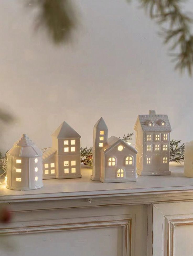 small white houses are lit up on the mantle