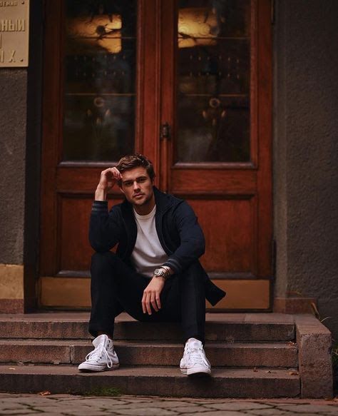 a man sitting on the steps in front of a door with his hands behind his head